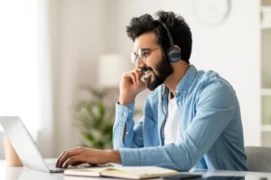 Ein Mann mit Headset sitzt lächelnd am Laptop und führt ein Online-Meeting durch. Digitale Schulungen zur UVV (Unfallverhütungsvorschrift) sorgen für rechtssichere Unterweisungen im Fuhrpark. Carano unterstützt Unternehmen mit digitalen Lösungen für effizientes und gesetzeskonformes Fuhrparkmanagement.