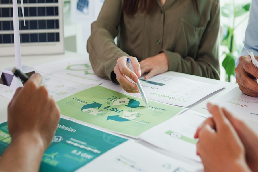 Three employees of a company with a fleet of vehicles are sitting at a table. The sustainability report is in front of them.