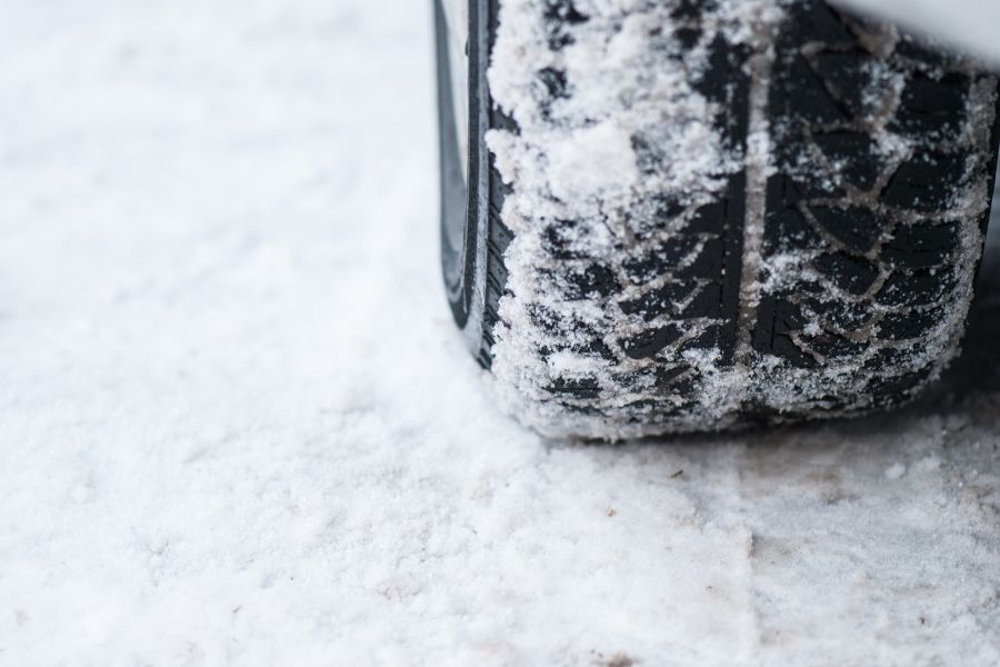 A winter tire on a road covered with snow.