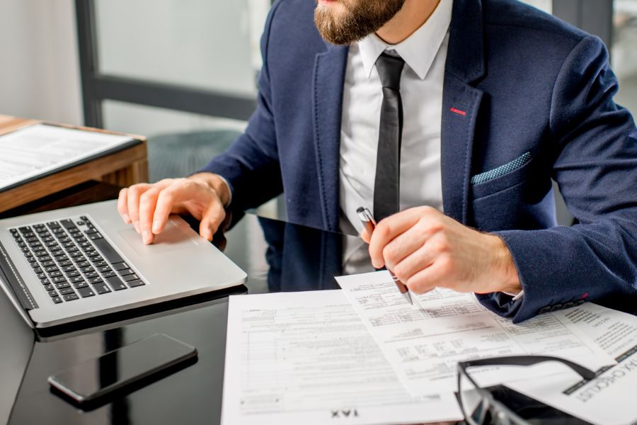An employee sits at a desk and works with documents. A symbolic image for the operating license in the vehicle fleet.
