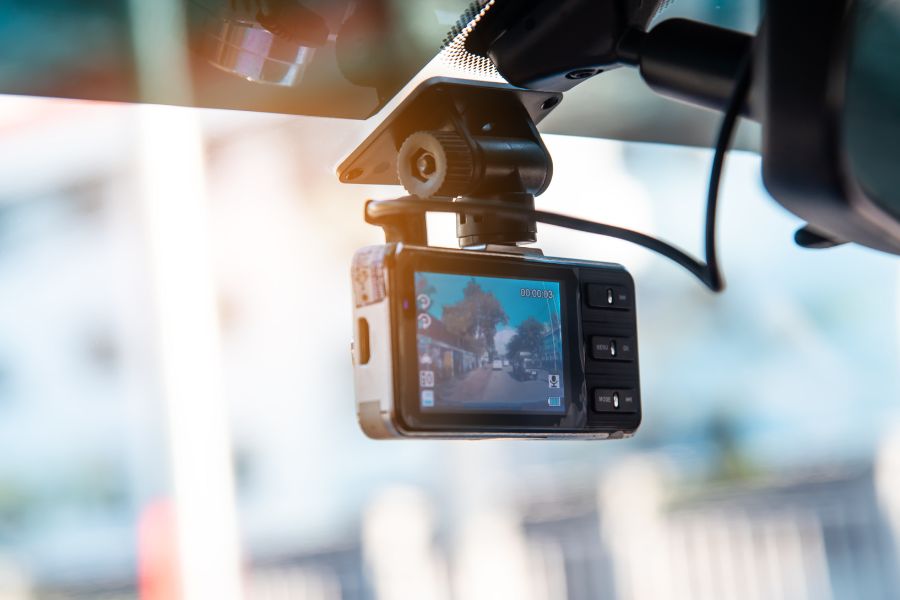 A dashcam is attached to the windshield of a vehicle.