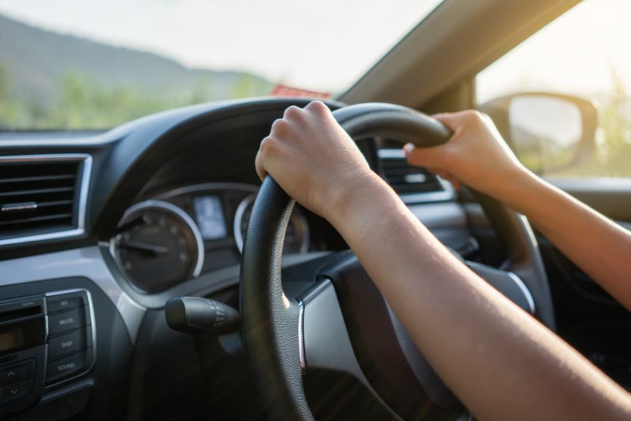 A driver sits at the wheel of a car and holds the steering wheel in his hand - a symbolic image for the driver profile.