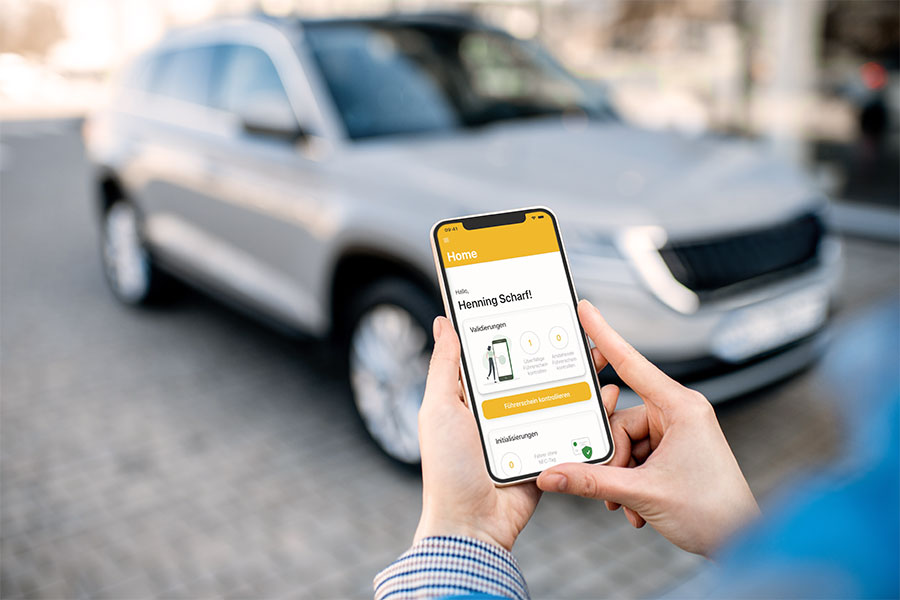 Person nutzt Smartphone-App zur elektronischen Führerscheinkontrolle vor einem Firmenfahrzeug. Die digitale Lösung von Carano ermöglicht eine zentrale, revisionssichere Dokumentation und unterstützt transparentes Fuhrparkmanagement bei vielen Fahrern und Standorten.