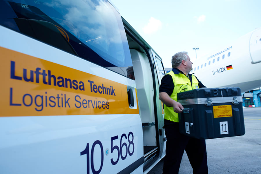Ein Mitarbeiter von Lufthansa Technik Logistik Services entlädt Material aus einem Servicefahrzeug auf dem Vorfeld. Der Bericht zeigt, wie 676 Fahrer an 8 Standorten mithilfe der elektronischen Führerscheinkontrolle von Carano rechtssicher, zentral dokumentiert und effizient im Fuhrpark gesteuert werden.