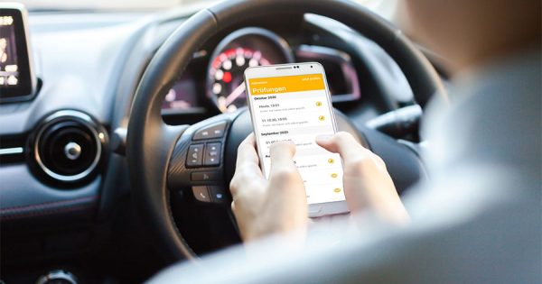 A person sits in a car and uses an app for digital driver's license checks. Employers are required by law to check driving licenses regularly. Carano offers legally compliant, digital solutions for automated checks with seamless documentation - for greater safety and simple implementation of legal regulations in fleet management.