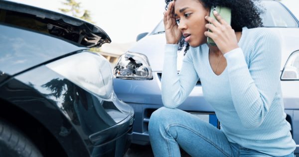 A stressed driver talks on the phone in front of two damaged cars. The scene shows the effort involved in accidents. Claims management software facilitates digital reporting and documentation. Fleet+ offers integrated claims management, bundles images, appraisals and invoices centrally and enables efficient analysis of key areas of damage.